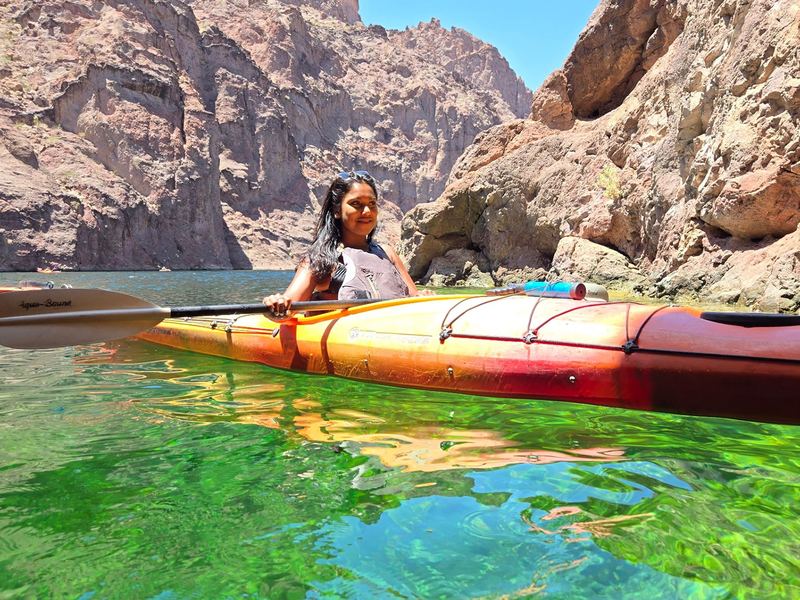 Black Canyon Kayak Tour - A kayaker glides through emerald water beneath the towering rock walls of Black Canyon.