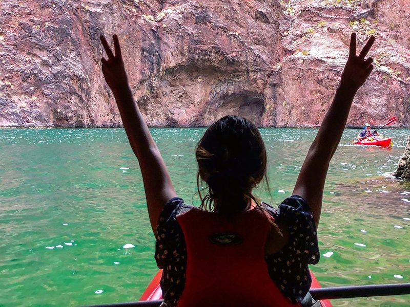 Black Canyon Kayak Tour - A paddler celebrates inside a shaded canyon cove while another kayak crosses the turquoise water.