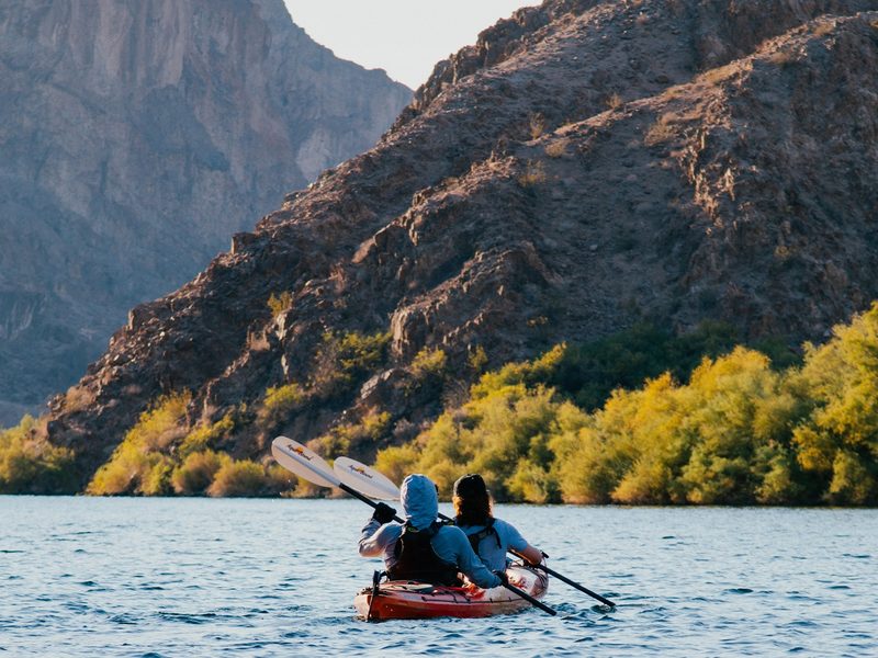 Black Canyon Kayak Tour - Two paddlers explore calm water framed by sunlit canyon walls and golden desert vegetation.