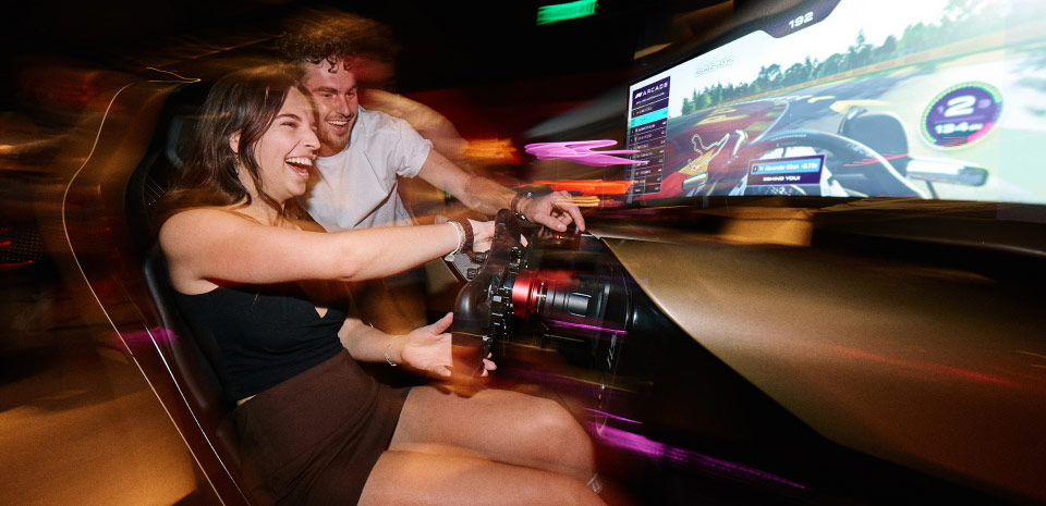 Rows of glowing racing simulators and a cocktail bar at a Las Vegas sim-racing venue
