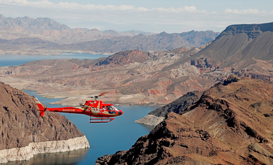 Helicopter flying below the rim of the Grand Canyon above the Colorado River