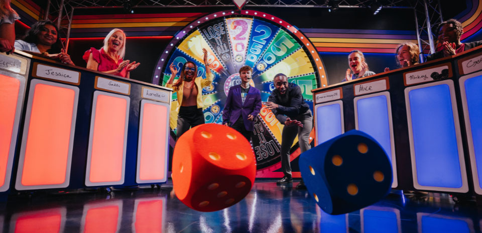 Two teams competing on a brightly lit live game-show stage in Las Vegas