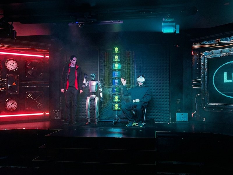 HACKED - Keelan Leyser, a humanoid robot and a VR-equipped participant share the stage during HACKED.
