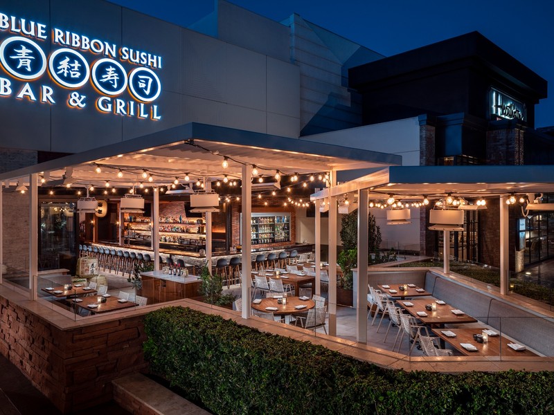 Blue Ribbon Sushi Bar & Grill offers an inviting open-air patio illuminated by warm string lights after sunset.