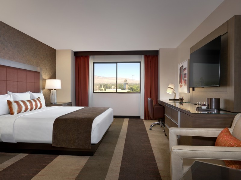 A king guest room at Santa Fe Station offers a comfortable bed, work area, seating and views toward the surrounding valley.