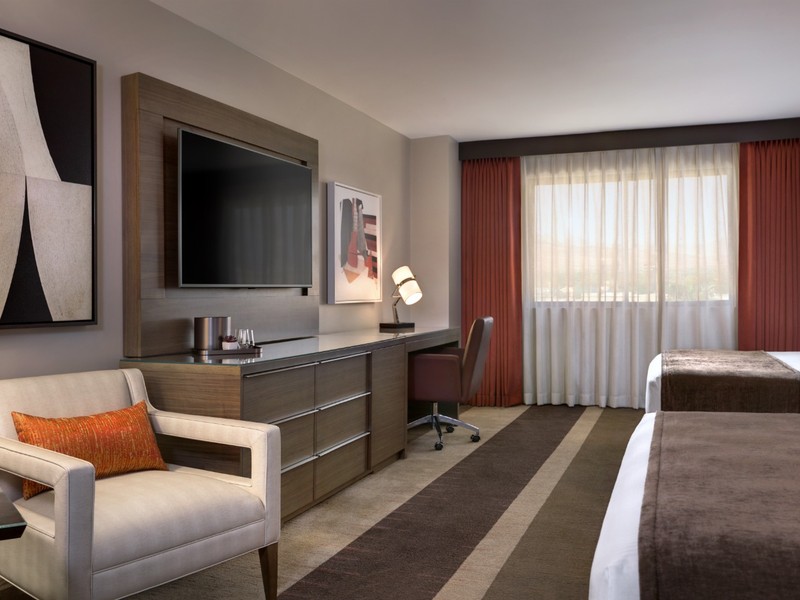 Another view of a two-queen room highlights the contemporary décor, large television, seating area and bright window.