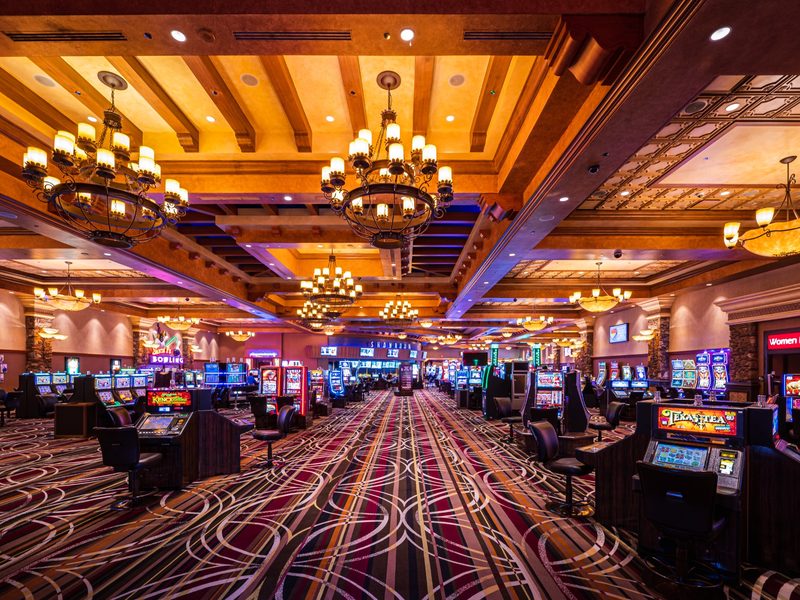 A wide casino corridor blends slot gaming with dramatic arches, patterned carpeting and easy access to nearby amenities.