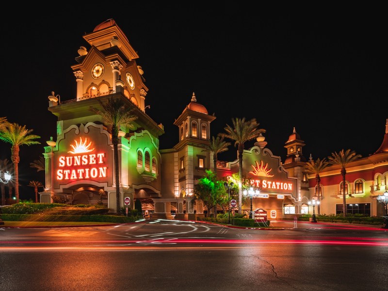 Sunset Station glows after dark, with its signature tower, palm-lined entrance and warm exterior lighting creating a striking nighttime arrival.