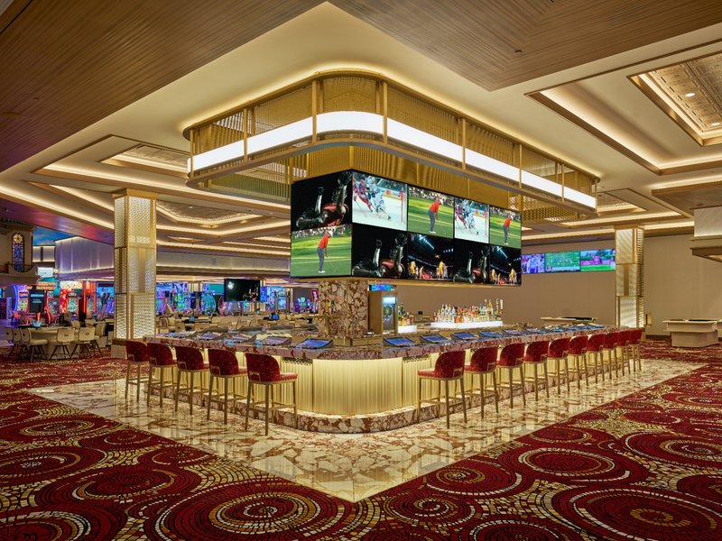 A polished casino bar pairs wraparound seating with multiple sports screens, giving guests a comfortable spot to sip and watch the action.